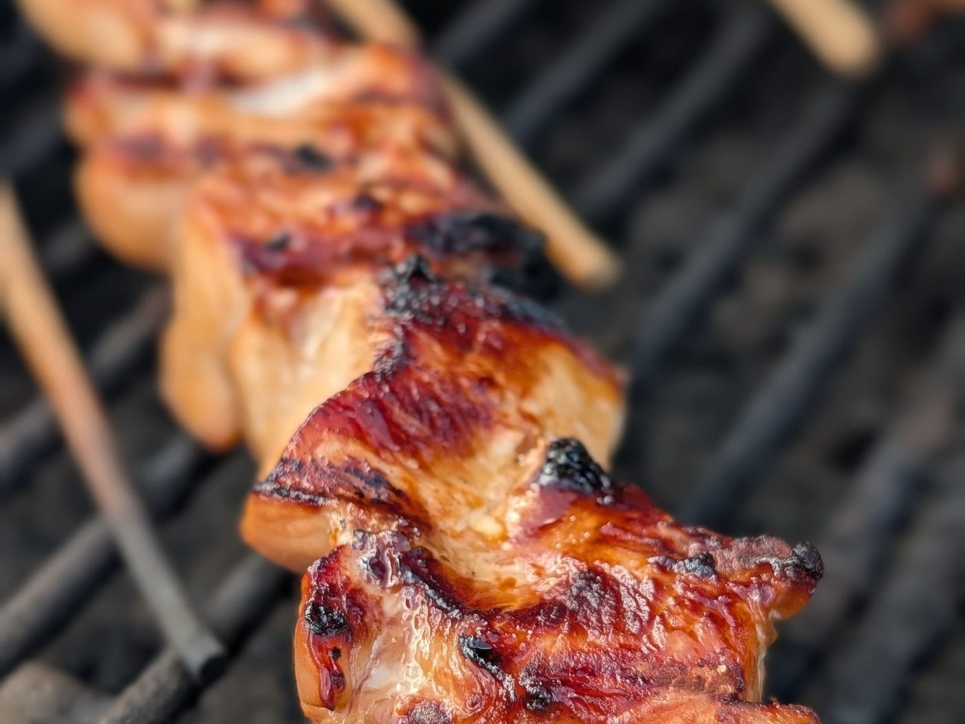 Charred grilled chicken skewers on a barbecue